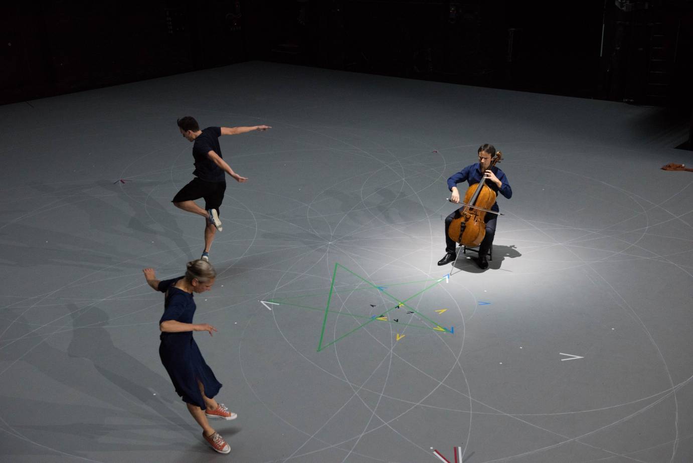 Aerial shot of the taped designs on the floor with the dancers and cellist